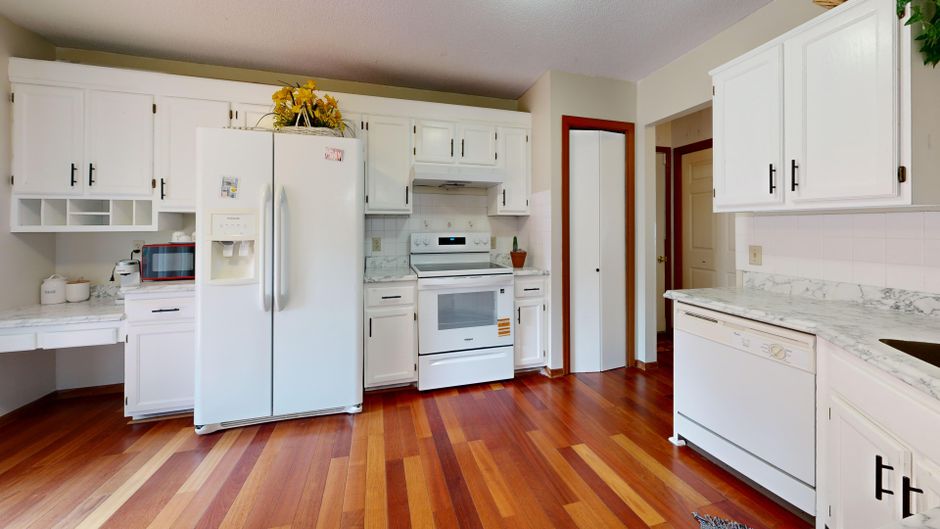 A kitchen with reddish hardwood flooring