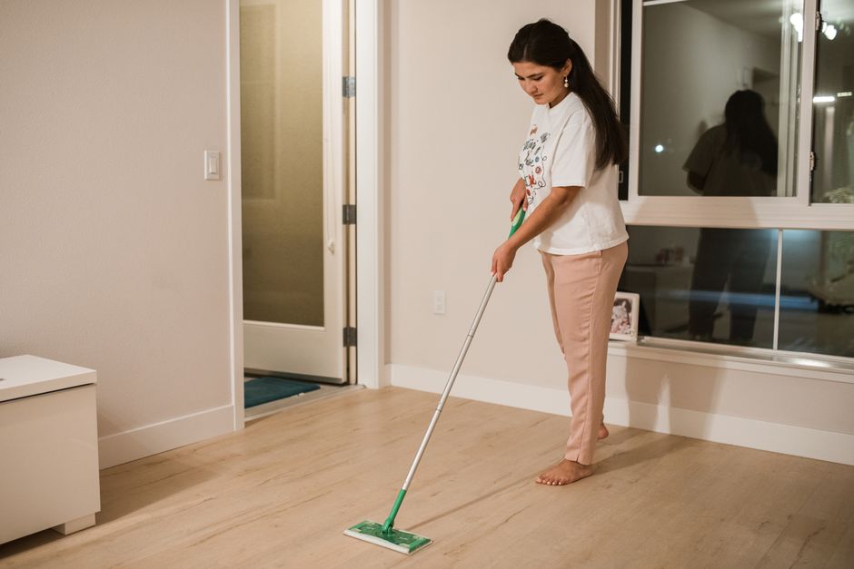 A freshly refinished hardwood floor being cleaned with a dry dust mop