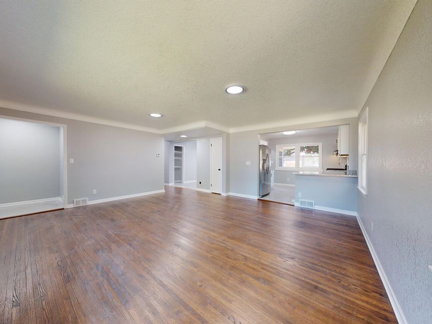 An empty living room with hardwood flooring cleared of furniture and rugs ahead of refinishing work