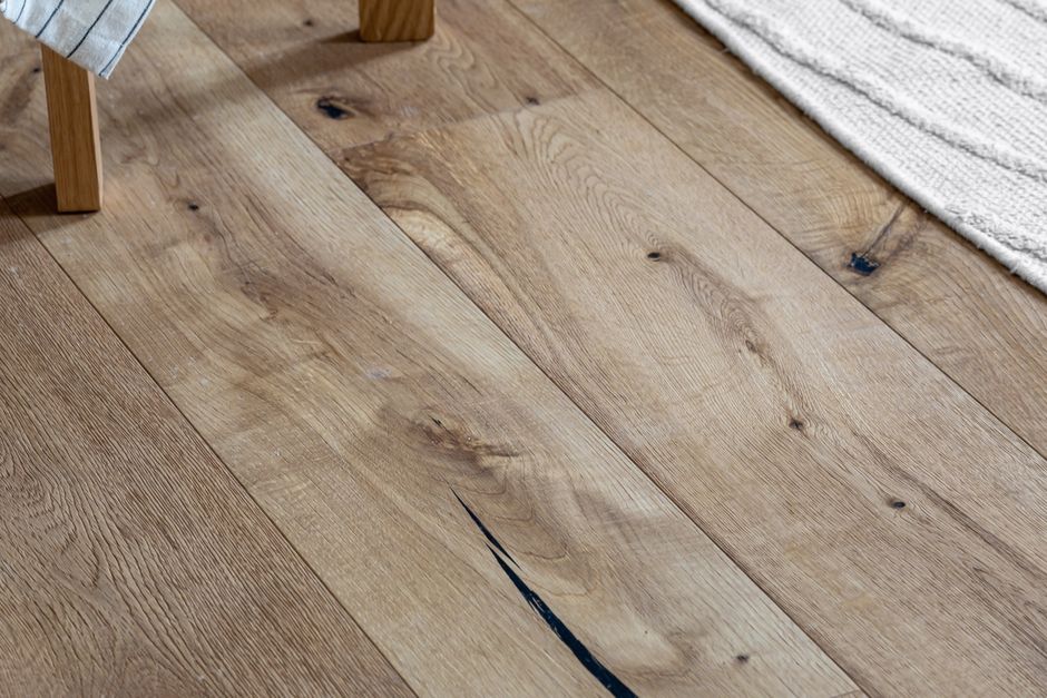 Close-up of a hand applying finish to a section of hardwood flooring