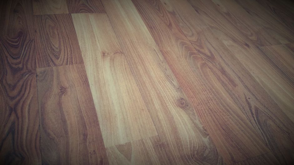 A hardwood floor board showing a patched, differently toned repair section