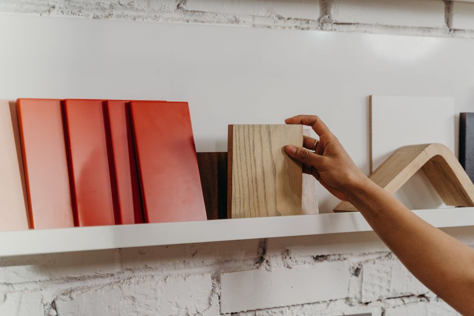 A hand selecting a wood-tone finish sample from a row of swatches